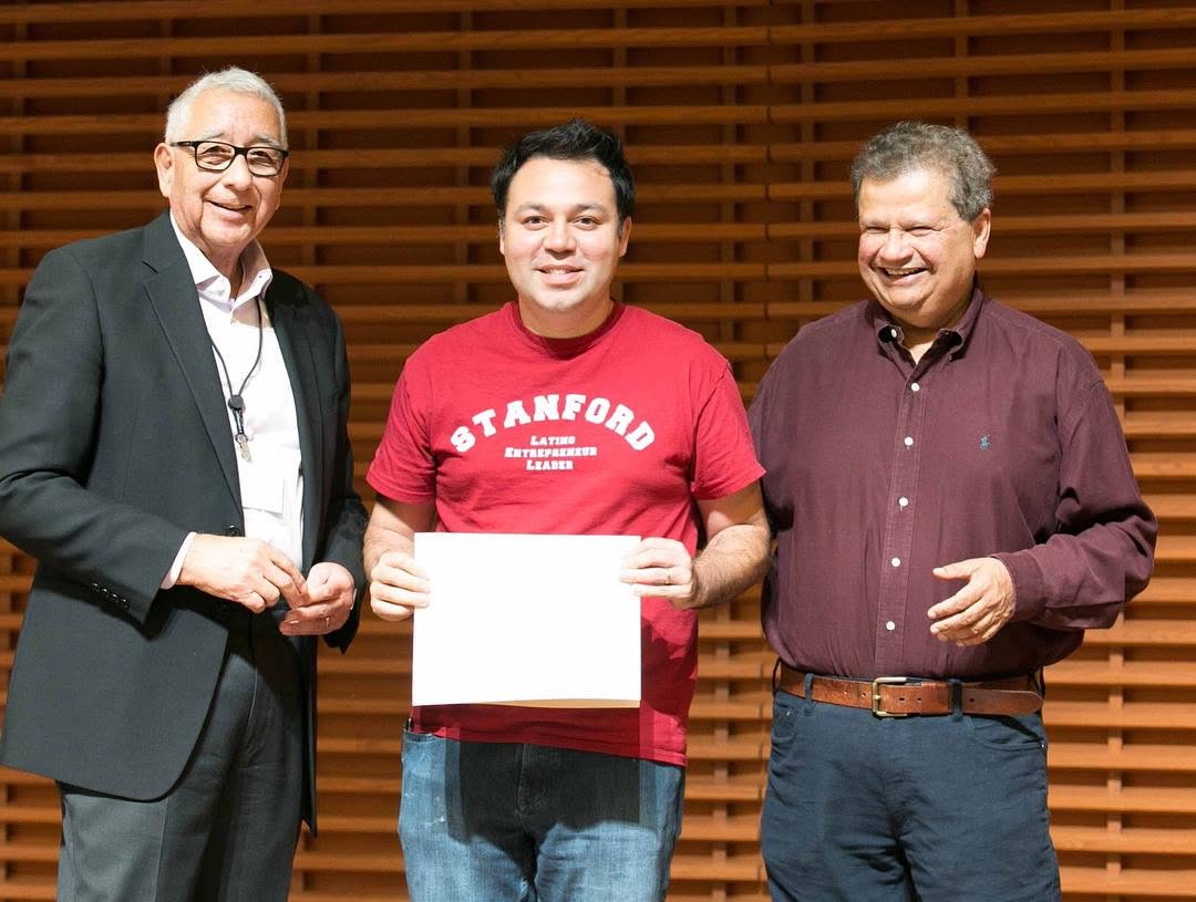 Robert De Los Santos in a Stanford Latino Entrepreneur Leader shirt receiving a certificate